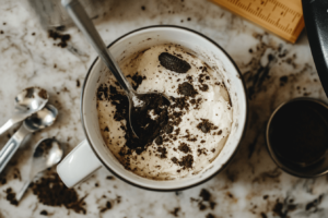 Crushed Oreos mixed with milk in a microwave-safe mug for Oreo Mug Cake.